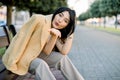 Summer sunny lifestyle fashion portrait of young stylish Asian woman, wearing trendy colorful outfit, sitting on city Royalty Free Stock Photo