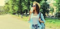 Summer sunny portrait of beautiful smiling young woman with cup of coffee wearing a straw hat and backpack in the city park Royalty Free Stock Photo