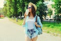 Summer sunny portrait beautiful smiling young woman with cup of coffee wearing a straw hat and backpack in the city park Royalty Free Stock Photo