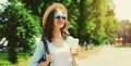 Summer sunny portrait beautiful smiling young woman with cup of coffee wearing a straw hat and backpack in the city park Royalty Free Stock Photo