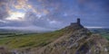 Summer sunrise on Brentor showning St Michael's church atop the tor with dramatic weather clouds of showers and mist, on the