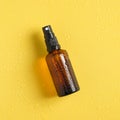 Summer sunscreen lotion bottle in droplets of water on yellow background. Flat lay, top view. Summer sun protection concept