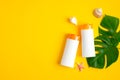 Summer sunscreen lotions bottles on yellow background with tropical leaves. Top view with copy space. Sun protection cosmetic