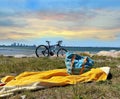 Summer sunset on blue cloudy sky  bike and women bag on yellow towel at green grass on beach on horizon Tallinn panorama view from Royalty Free Stock Photo