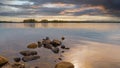 Summer sunset on the lake. Beautiful  water landscape with stones, sun reflection and cloudy sky Royalty Free Stock Photo