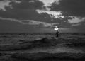 Summer sunset view of a beach under a cloudy sky with a single sup surfer silhouette in black and white