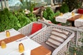 Summer terrace veranda of the cafe. Cozy gray wicker chairs with cushions, served tables and green bushes Royalty Free Stock Photo