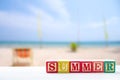 summer text wooden blocks on table with on blur beach