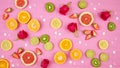 Summer theme background with fruit, citrus and flowers on pink backdrop.