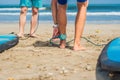 Summer time and active rest concept. Young surfer man beginner fastens leash across leg, going to surf on big barral