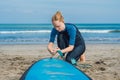 Summer time and active rest concept. Young surfer woman beginner fastens leash across leg, going to surf on big barral