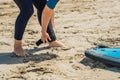 Summer time and active rest concept. Young surfer woman beginner fastens leash across leg, going to surf on big barral