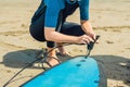 Summer time and active rest concept. Young surfer woman beginner fastens leash across leg, going to surf on big barral