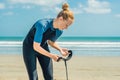 Summer time and active rest concept. Young surfer woman beginner fastens leash across leg, going to surf on big barral