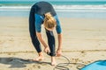 Summer time and active rest concept. Young surfer woman beginner fastens leash across leg, going to surf on big barral