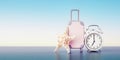 Travel concept with baggage, seashell and alarm clock on blue sky background at sunrise. Banner