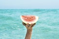 Summer time concept lifestyle. One hand holding fresh red watermelon piece against a blue ocean sea water background. Healthy food Royalty Free Stock Photo