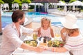 Nice pleasant family having meal near the pool