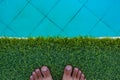 Summer time vacation season swimming pool hotel relaxation space background with male bare feet on a synthetic grass floor, empty Royalty Free Stock Photo