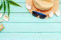 Summer travaling to the sea with straw hat, sun glasses, shells on mint green wooden background top view mock up