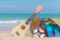 Summer Travel. Bikini and Flip-flops , hat, ukulele, and bag near beach chair on sandy beach against blue sea and sky background, Royalty Free Stock Photo