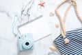 Summer travel composition on a marble background. Women`s desk with instant photo camera, striped beach bag, seashells and blank n Royalty Free Stock Photo