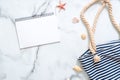 Summer travel composition on a marble background. Women`s desk with striped beach bag, seashells and blank notepad. Lifestyle of Royalty Free Stock Photo