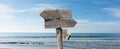 Summer travel destinations options.  Direction road sign with wooden arrows on beach and sea Royalty Free Stock Photo