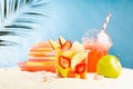 Summer travel and holiday background - picnic with cold drink, fresh fruit salad takeaway, sun hat on hot sunny sandy beach. Royalty Free Stock Photo