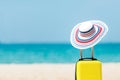 Summer traveling and planning with yellow suitcase luggage with big hat fashion in the sand beach. Royalty Free Stock Photo