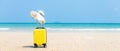 Summer traveling and tourism planning with yellow suitcase luggage with big hat fashion in the sand beach. Royalty Free Stock Photo