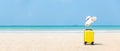 Summer traveling and tourism planning with yellow suitcase luggage with big hat fashion in the sand