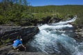 Summer trekking in Sweden. Man fills bottle with clear drinking water from river Abiskojokk in Abisko National Park in northern Sw