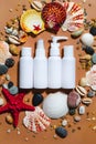 Summer trevel size cosmetics flat lay. Beauty composition with sea shells, sand on beige. Cream sample white bottles