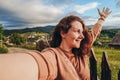 Summer trip to the mountains. A young woman takes a selfie on top of a mountain in the evening at sunset. Royalty Free Stock Photo