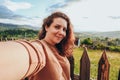 Summer trip to the mountains. A young woman takes a selfie on top of a mountain in the evening at sunset. Royalty Free Stock Photo