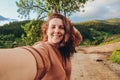 Summer trip to the mountains. A young woman takes a selfie on top of a mountain in the evening at sunset. Royalty Free Stock Photo