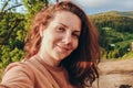 Summer trip to the mountains. A young woman takes a selfie on top of a mountain in the evening at sunset. Royalty Free Stock Photo