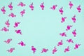 Summer tropical background, frame of chaotic pattern made of numerous pink flamingo confetti on turquoise pastel background,