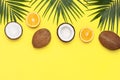 Summer tropical composition. Green tropical leaves of palm trees, coconut, orange on bright yellow background. Flat lay Royalty Free Stock Photo
