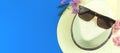 Summer vacation accessories flat lay composition with straw hat and sunglasses on a blue background, top view photo with Royalty Free Stock Photo