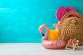 Summer vacation background with orange juice, fashion bag and flamingo pool float on wooden table Royalty Free Stock Photo