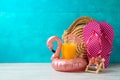 Summer vacation background with orange juice, fashion bag and flamingo pool float on wooden table Royalty Free Stock Photo