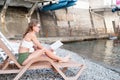 The beautiful young woman sitting on the sun lounger reading a book Royalty Free Stock Photo