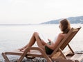 The beautiful young woman sitting on the sun lounger reading a book Royalty Free Stock Photo