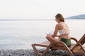 The beautiful young woman sitting on the sun lounger reading a book Royalty Free Stock Photo