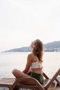 The beautiful young woman sitting on the sun lounger listening to the music and dancing Royalty Free Stock Photo