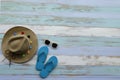 Summer and vacation on the beach concept.Top view lady straw hat, sunglasses and flip flops on blue wooden background.