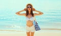 Summer vacation, beautiful happy smiling woman in bikini swimsuit and straw hat with bag on the beach on sea coast background on Royalty Free Stock Photo