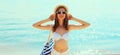 Summer vacation, beautiful happy smiling woman in bikini swimsuit and straw hat with bag on the beach on sea coast background on Royalty Free Stock Photo